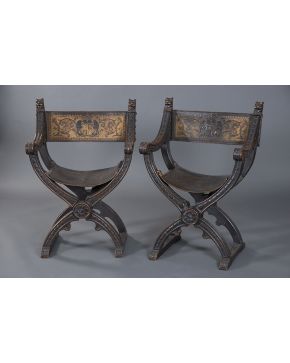 713-Pareja de sillas jamugas en madera tallada con remates de cabezas de león. S. XIX. Asiento y respaldo en cuero labrado.