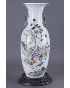 1024-Jarrón en porcelana china tipo Familia Verde. C. 1900. Inscripciones en el reverso y anverso con escena cotidiana. Sobre peana en madera.