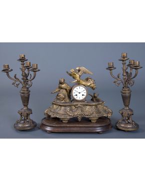 690-Antigua guarnición formada por reloj de sobremesa con figuras de la Anunciación con pareja de candelabros de cuatro luces en metal dorado. Esfera con 