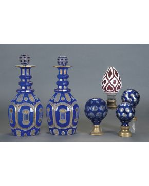 1232-Decorativa pareja de botellas con tapa en cristal tallado y facetado azul cobalto con detalles de palmetas y filos en dorado. C. 1900.