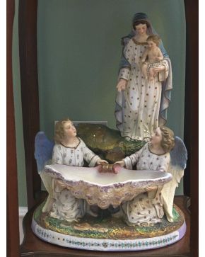 510-Decorativa benditera en biscuit policromado representando Virgen con niño y ángeles. Con marcas.