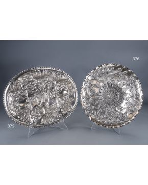 376-Antigua bandeja circular en plata española. Ley 916. Decoración repujada con centro relevado y decorado con girasol. y flores en el alero. Con marcas.