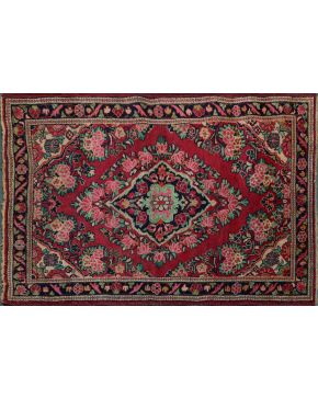 874-Alfombra persa sarogh. Rombo central formado por motivos florales sobre fondo rojo. Cenefa triple con franja central azul. Colores complemetarios: ver