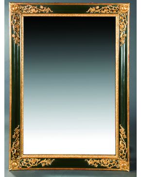 590-Gran espejo rectangular en madera tallada y dorada y pintada en verde con esquinas decoradas con elementos vegetales y florales.