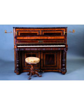 775-Piano de pared isabelino de dos pedales Aucher en palma de caoba y palosanto con candiles de bronce. Se acompaña de su banqueta. Ppios s. XX.