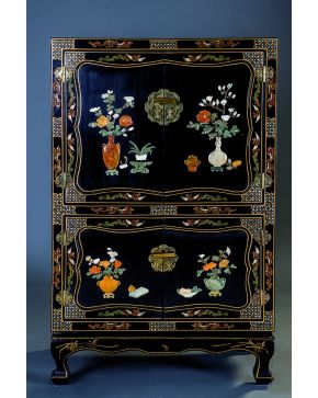 1084-Mueble oriental en madera lacada en negro con dobles puertas al frente decoradas con aplicaciones de piedras duras formando jarrones con flores y pája