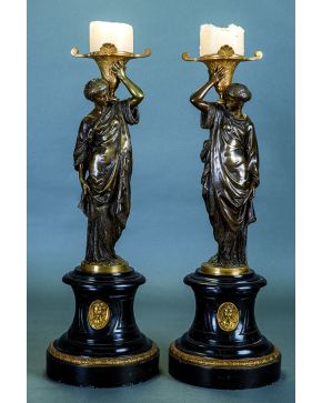 1037-Pareja de candeleros Imperio en bronce dorado. S. XIX. Fuste en forma de dama clásica sosteniendo una copa. Sobre peana en madera ebonizada con medall