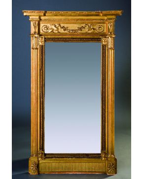 717-Gran espejo estilo Luis XVI en madera tallada y dorada con motivos de mascarones y contario de perlas en los bordes. Remate con friso decorado con gri