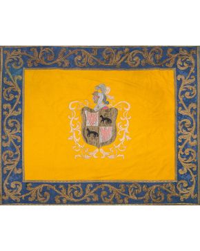 500-Clásico repostero en seda bordada con cenefa azul y campo central amarillo con escudo herádico en el centro coronado por cimera. s. XX.