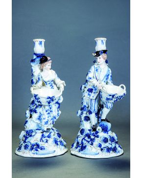 580-Pareja de candeleros en porcelana esmaltada en azul de Sitzendorf. Base decorada con flores en relieve y apoyados en el fuste una figura femenina y ot