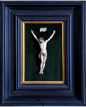 1132-Antiguo Cristo en marfil tallado. s.XIX. con cuatro clavos y toques de negro en pelo y paño de pureza. Enmarcado y dispuesto sobre terciopelo verde.