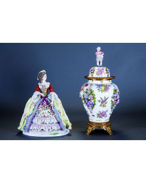 821-Gran figura en porcelana polícroma de Capodimonte representando a una dama vestida a la moda francesa del s. XVIII con miriñaque y parnier y sujetando