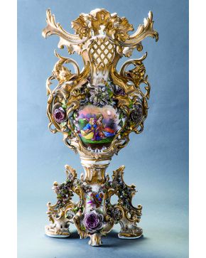 849-Gran jarrón en porcelana Viejo París. con profusa decoración vegetal y floral enmarcando una escena cortesana en el frente. Asas en forma de dragón y 