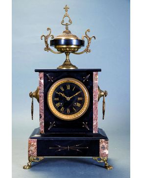 637-Reloj de sobremesa Napoleón III. Francia. S. XIX. en mármol negro y jaspeado con remate de copa clásica y detalles en bronce dorado. Esfera con numera