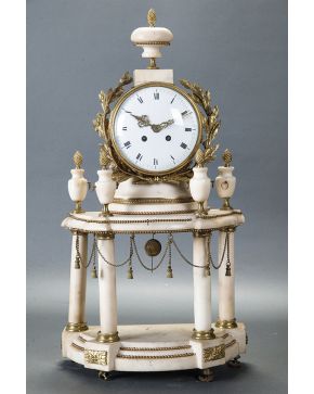 695-Reloj de sobremesa estilo Luis XVI. Francia s. XIX en alabastro y bronce dorado con base a modo de templete. Esfera en porcelana blanca con numeración