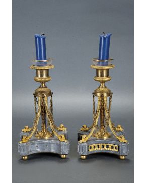 781-Pareja de candeleros franceses estilo Imperio en bronce dorado con base de mármol gris. Fuste helicoidal sujeto por cuatro patas con remate vegetal y 