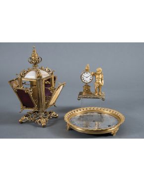 368-Centro de mesa circular en bronce dorado con galería de estilizadas palmetas y base de espejo. Sobre tres patas en forma de rocalla con venera central
