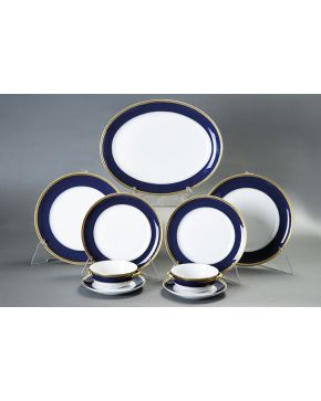 668-Vajilla en porcelana esmaltada de Vistalegre con ala azul cobalto y filo dorado. Formada por: 28 platos llanos. 16 servivios de consomé. 15 platos de 