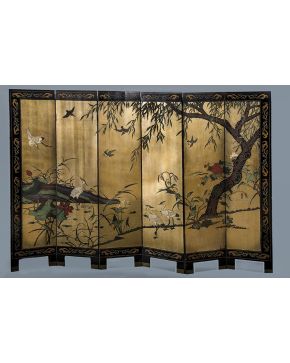 1090-Biombo chino s. XIX. formado por seis hojas lacadas en negro con decoración polícroma de elementos vegetales y grullas en relieve sobre fondo dorado y