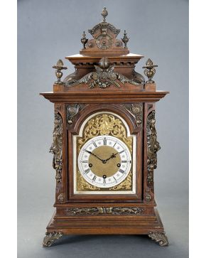334-Reloj tipo bracket alfonsino. S. XIX. con caja en madera tallada y aplicaciones en bronce dorado con esfinges en las esquinas y mascarones en los late