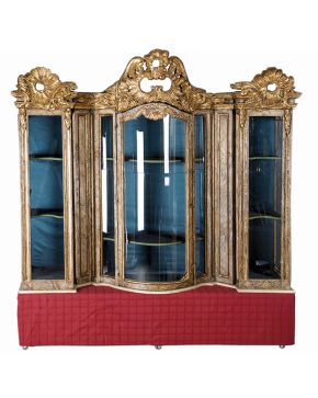486-Original mueble vitrina de frente ondulante en madera tallada. dorada y policromada imitando mármol con remate superior barroco decorado con tornapunt