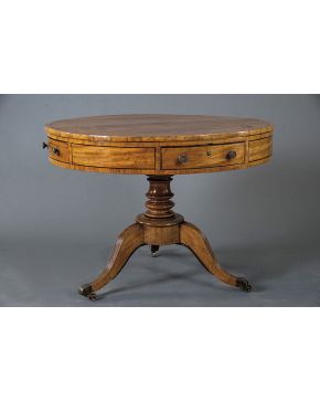 526-Mesa inglesa de tambor en madera tallada con pie central dividido en cuatro patas rematadas en rueda y cuatro cajones en la cintura. s. XIX. Con llave