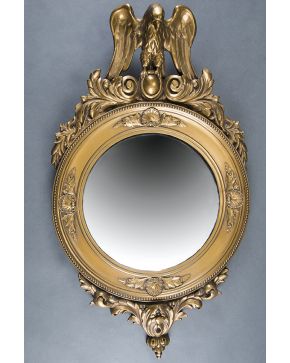 478-Espejo circular en madera tallada y dorada decorado con veneras y contario de perlas e importante copete con figura de águila posada sobre una ova fla