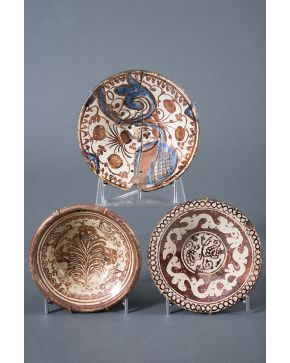 503-Lote formado por tres platos en cerámica de reflejo dorado de Manises uno de ellos con toques de azul consolidado y lañado.s. XVI-XVII. Desperfectos.