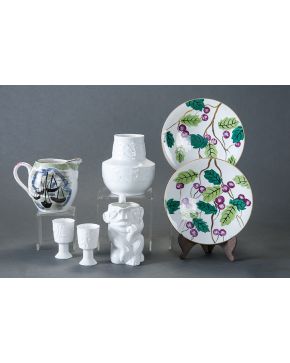 571-Lote en porcelana española de Castro formado por jarrón. jarra de los vicios y dos copas. Decoraciones en relieve y marcas en la base. Algún piquete