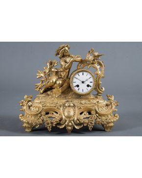 739-Reloj de sobremesa en bronce dorado estilo Luis XV con figura de muchacho en bulto redondo. Base profusamente decorada con guinaldas. rocallas y eleme