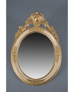 991-Gran espejo oval en madera tallada. dorada y pintada con copete de rocalla. tornapuntas. flores y espejo central. s. XIX. Algún desperfecto.
