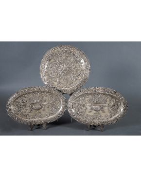 513A-Lote formado por tres bandejas en plata. dos de ellas pareja ovales con decoración cincelada en el campo de jarrón con flores; y la tercera circular c