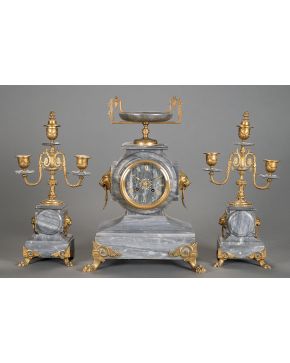 502-Reloj de sobremesa con guarnición de candelabros de tres luces en mármol gris. con aplicaciones en  bronce dorado. Francia. S. XIX.