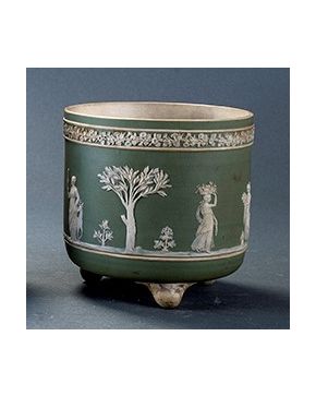 1503-Macetero en porcelana de Weedgood con decoración en relieve de escenmas clásicas y friso superior de flores sobre fondo verde. Un pelo.