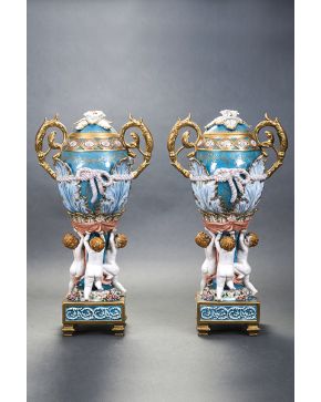 323-Decorativa pareja de copas con tapa en porcelana esmaltada y dorada de Sévres. ff.s.XIX. Forma ovoide. con cuatro querubines en el fuste sosteniendo l