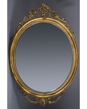 314-Gran espejo con marco oval en madera tallada y dorada. con copete calado y remate con decoración vegetal. S. XIX.