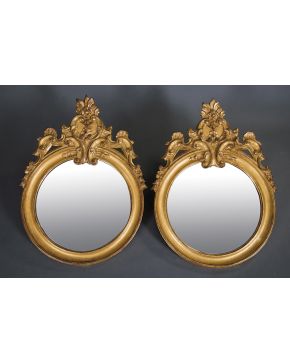 841-Pareja de espejos circulares con marco en madera tallada y dorada rematado en copete vegetal. de tornapuntas y flores. S. XIX.