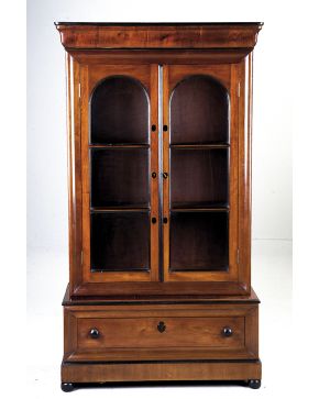520-Librería en madera tallada de caoba con cuerpo superior de doble puerta acristalada y compartimentado en tres alturas. cajón inferior y perfiles eboni