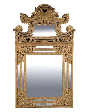 355-Gran espejo en madera tallada y dorada con importante copete y profusa decoración en relieve de elementos vegetales. tornapuntas y rocallas. 