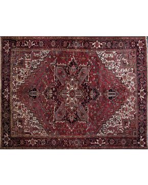 320-Antigua alfombra persa HERIZ. en lana anudada a mano. Rosetón central polilobulado sobre fondo totalmente cubierto de muestras vegetales y diseños flo