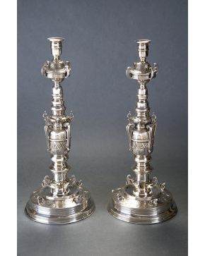 680-Pareja de candeleros en plata española punzonada siguiendo modelos renacentistas. Decoración de tornapuntas y original base circular con cabezas de bó