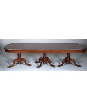 382-Gran mesa de comedor estilo inglés en madera de caoba hondureña con tres patas con decoración relevada vegetal terminas en garra sobre bola.