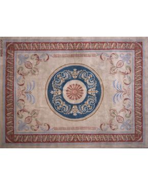 579-Importante alfombra en lana de nudo español. diseño Savonnerie. firmada Miguel Stuyck. Medallón central en azul y decoración con motivos vegetales sob