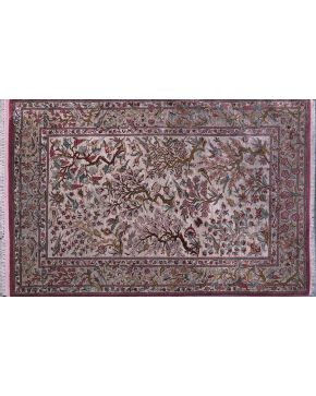 366-Alfombra iraní en seda y lana con decoración vegetal de ramas. hojas. y aves sobre campo beige con tonos rosas y marrones.