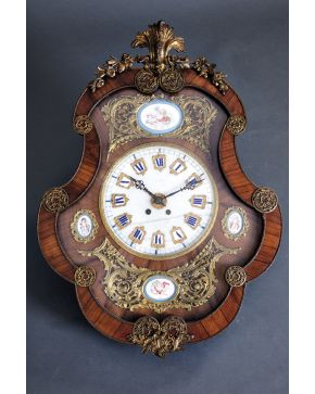 425-Reloj de pared en madera tallada ff. s. XIX. Con aplicaciones de bronce. esfera en mármol blanco con numeración romana y placas de porcelana con angel