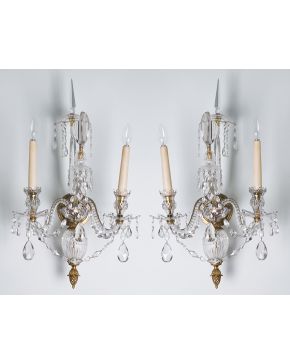 564-Pareja de apliques de dos luces en bronce y cristal	 con decoración de cuentas. gotas colgantes y copete de pináculo. Remate de piña.