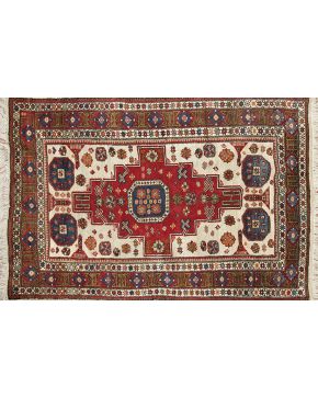 1037-Alfombra en lana con decoración de motivos geométricos y florales sobre campo beige. Cruz central en rojo y cenefa decorativa en tonos rojizos y verde