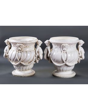 391-Pareja de maceteros en cerámica vidriada en blanco con pequeños faunos en relieve. cabezas de léon. y decoración de guirnaldas. Uno consolidado.