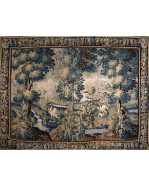 944-Tapiz verdure en lana S. XVII con representación de aves en paisaje y fondo de arquitecturas. Cenefa perimetral con jarrones con flores y elementos ve