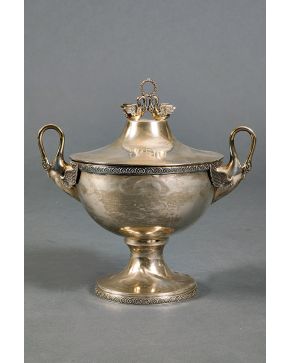 563-Centro en forma de copa con tapa en plata punzonada con marcas de Montejo. Friso y pie decorado con palmetas y remate y asas de cisnes. Alguna abollad